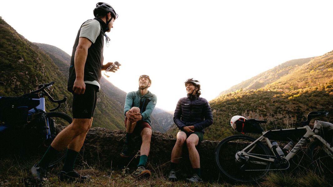 Long-Distance Cycling Nutrition Tips – Hydration and Fueling Breaks Nutrition advice when doing long-distance cycling—cyclists take a break to refuel and hydrate during a mountainous tour.